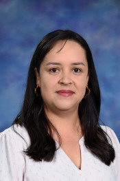 A woman with long dark hair, wearing a light blouse, smiles against a blue and purple background.