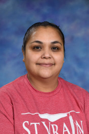 A smiling woman with long dark hair, wearing a red shirt, poses against a blue and purple background.