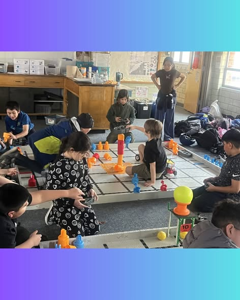 Children are engaged in a playful activity with colorful toys on a grid, while an adult supervises in the background.